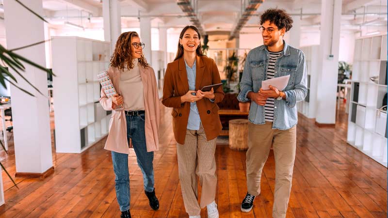 Três jovens adultos a caminhar num escritório moderno 